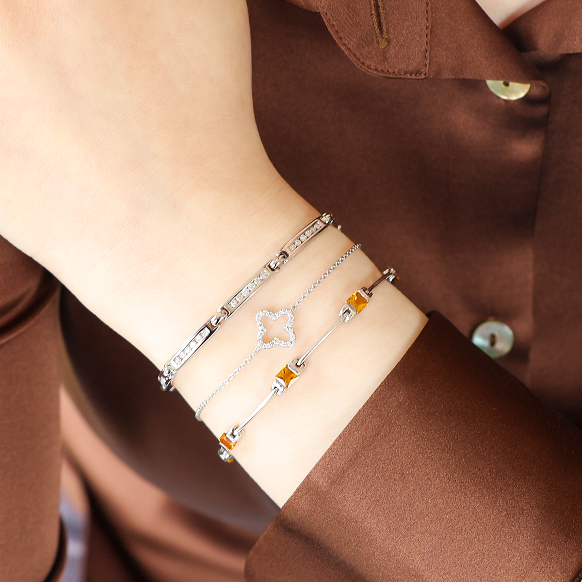 Model wears 9ct White Gold Diamond Channel Set Bar Link Bracelet, 9ct White Gold Diamond Set Clover Bracelet and 9ct White Gold Princess Cut Citrine Log Bracelet