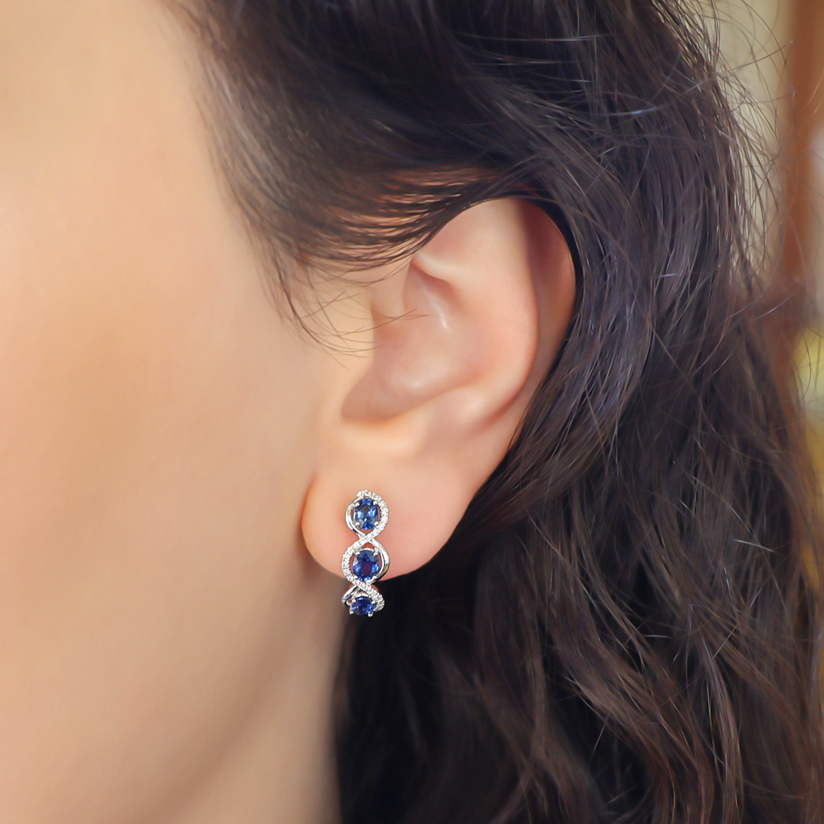 Model wears 18ct White Gold Oval Cut Sapphire & Diamond Infinity Hoop Earrings