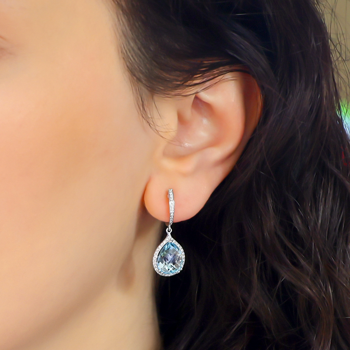 Model wears 9ct White Gold Pear Shaped Blue Topaz & Diamond Halo Drop Earrings