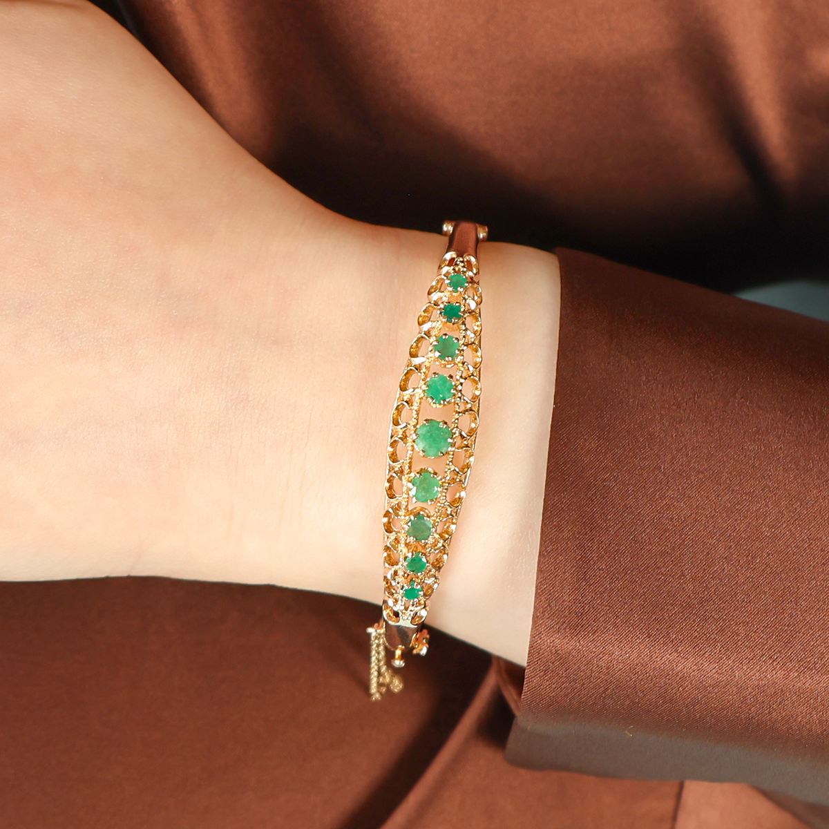 Model wears 9ct Yellow Gold Graduated Emerald Claw Set Hinged Bangle