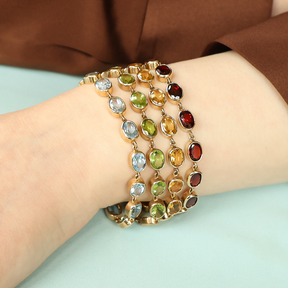Model wears a stack of 9ct Yellow Gold Blue Topaz, Peridot, Citrine & Garnet Bezel Set Bracelets