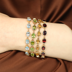 Model wears a stack of 9ct Yellow Gold Blue Topaz, Peridot, Citrine & Garnet Bezel Set Bracelets