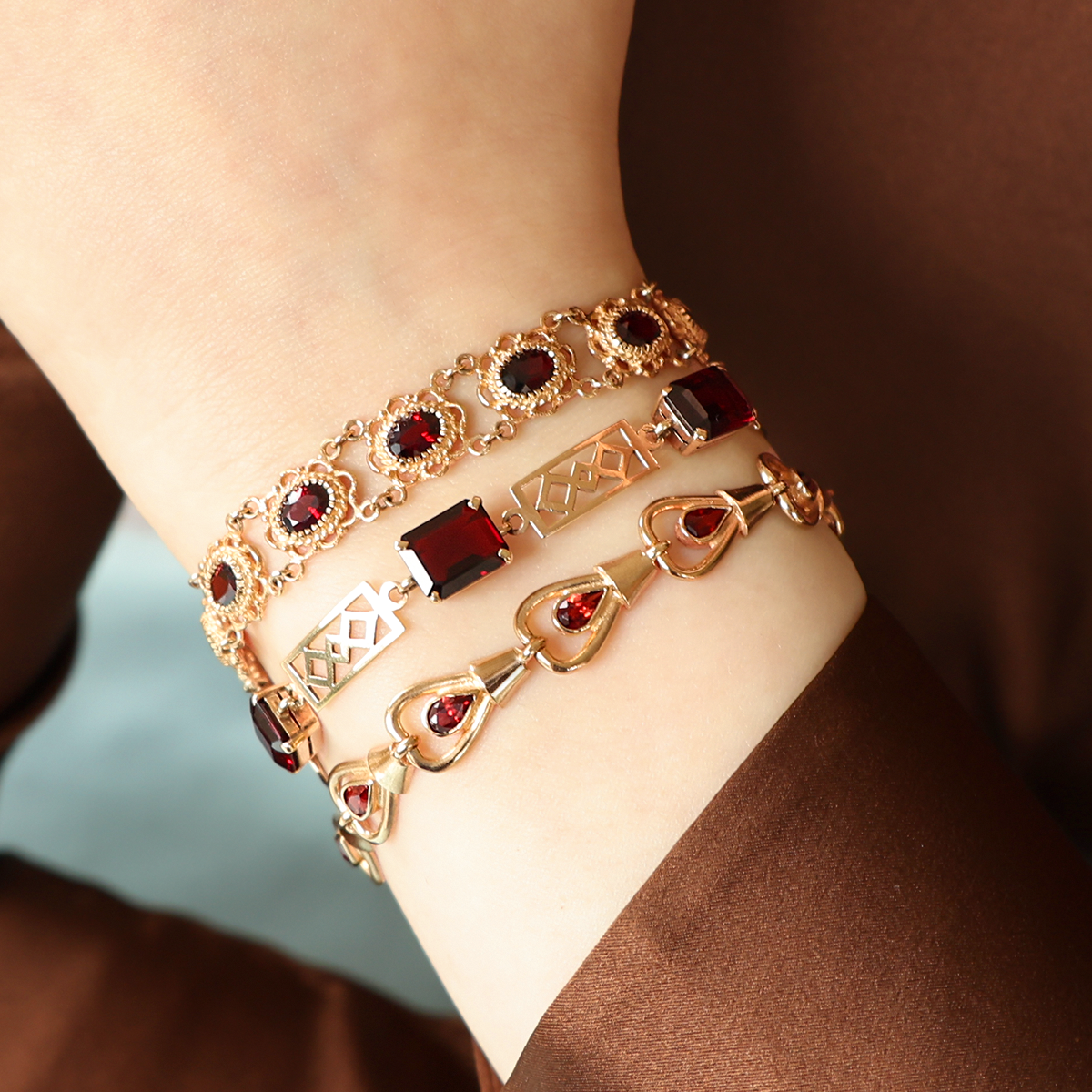 Model wears 9ct Yellow Gold Garnet Set Openwork Link Bracelet, 9ct Yellow Gold Victorian Style Garnet Bracelet & 9ct Yellow Gold Teardrop Garnet Set Bracelet