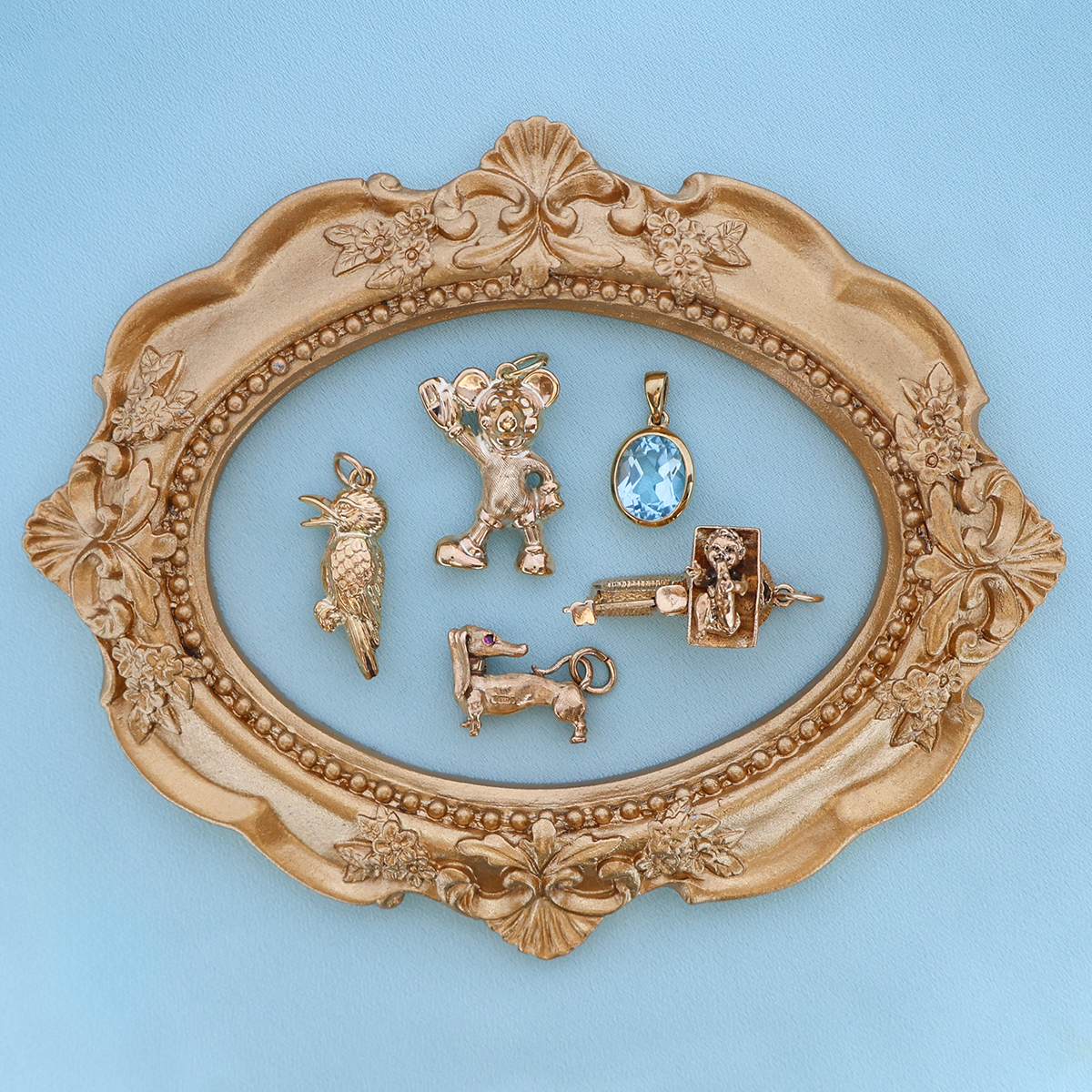 9ct Yellow Gold Hollow Kookaburra Bird Charm, 9ct Yellow Gold Hollow Mickey Mouse Pendant By Georg Jensen, 9ct Yellow Gold Oval Shaped Sky Blue Topaz Bezel Set Pendant, 9ct Yellow Gold Dachshund Sausage Dog With Ruby Eyes Charm & 9ct Yellow Gold Moveable Baby On Scales Charm