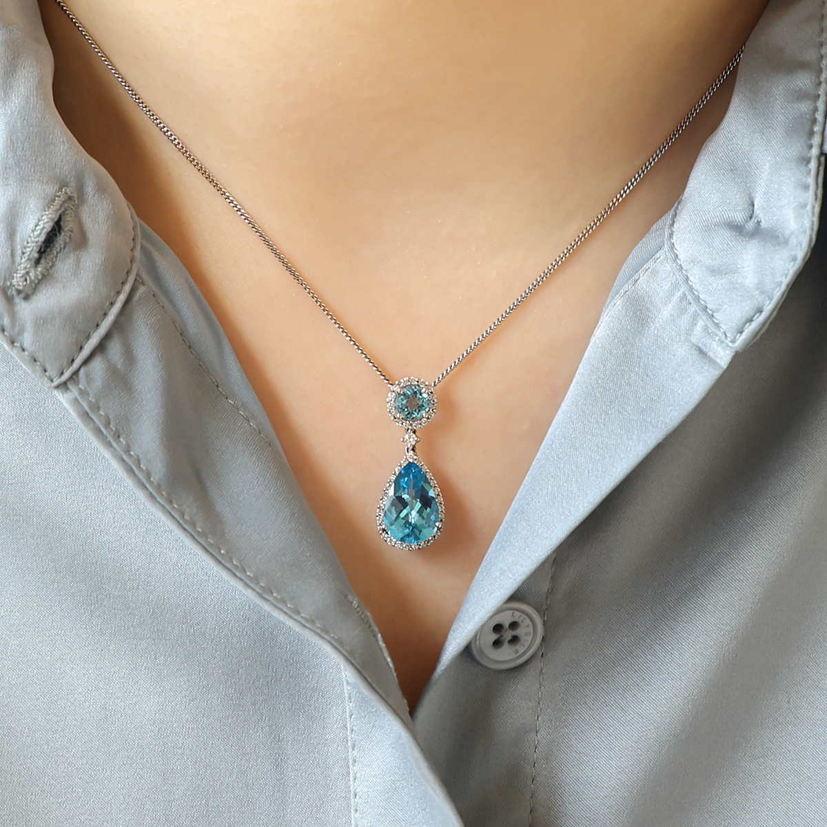 Model wears 18ct White Gold Blue Topaz & Diamond Halo Drop Pendant & Chain