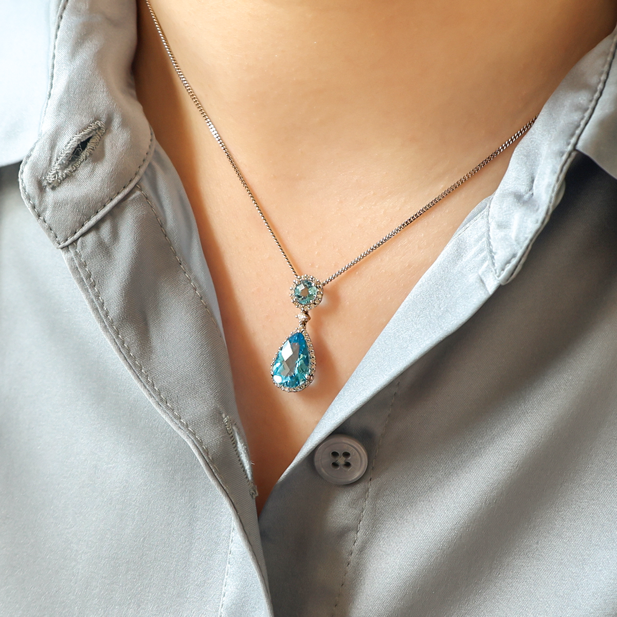 Model wears 18ct White Gold Blue Topaz & Diamond Halo Drop Pendant & Chain
