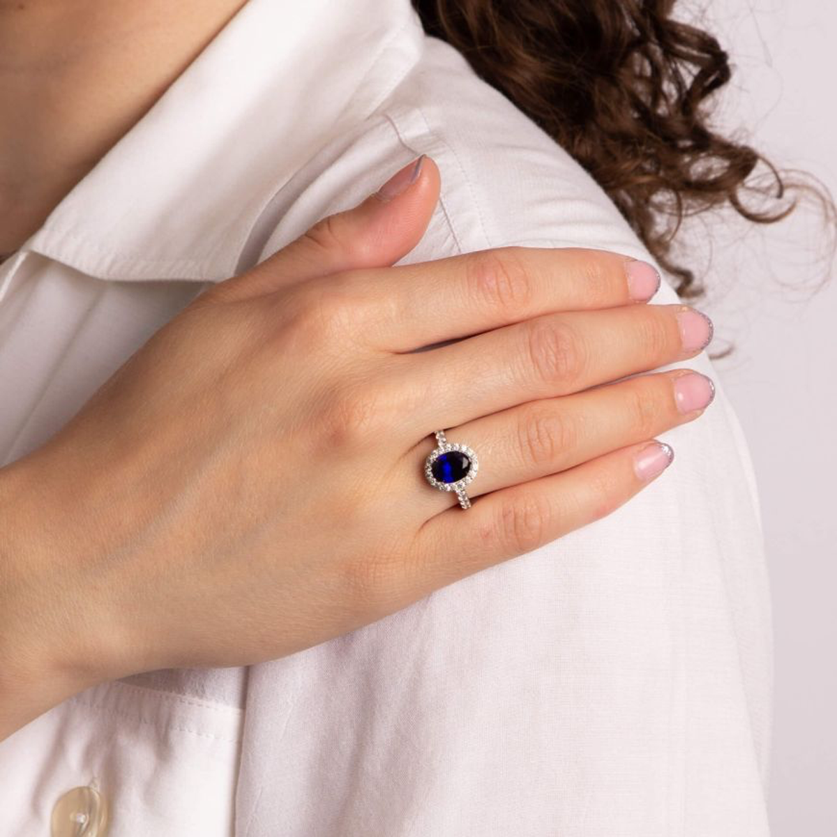 Model wears Sterling Silver Oval Blue Cubic Zirconia Halo & Shoulders Ring