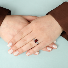 Model wears 9ct White Gold Emerald Cut Garnet Solitaire Ring With Diamond Shoulders