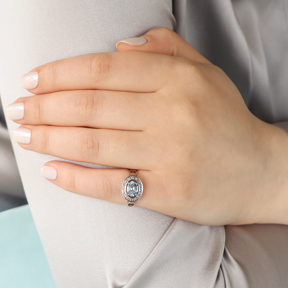 Model wears 9ct White Gold Oval Shaped Blue Topaz & Diamond Halo Ring