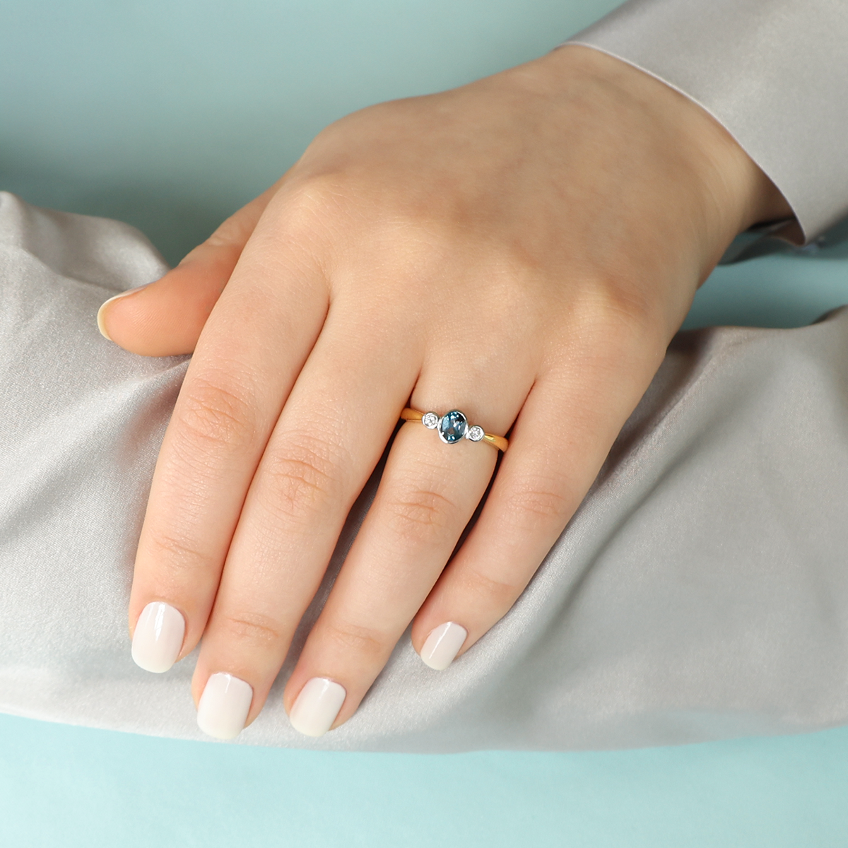 Model wears 18ct Yellow Gold Blue Topaz & Diamond Bezel Set Trilogy Ring