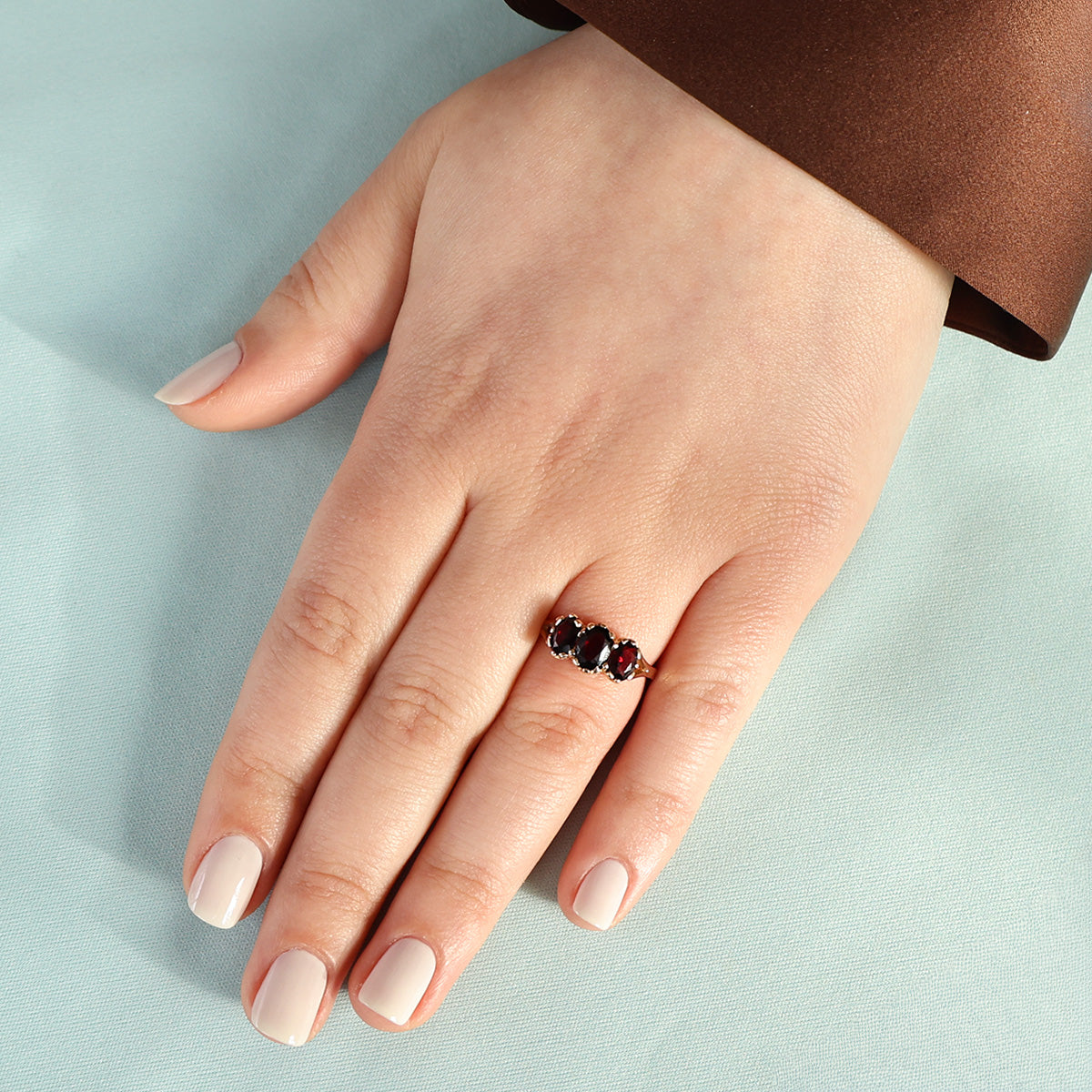 Model wears 9ct Yellow Gold Oval Shaped Garnet Trilogy Ring
