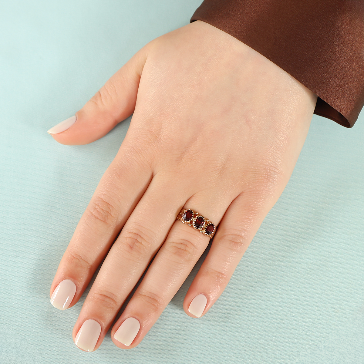 Model wears 9ct Yellow Gold Oval Shaped Garnet Trilogy Hearts Ring