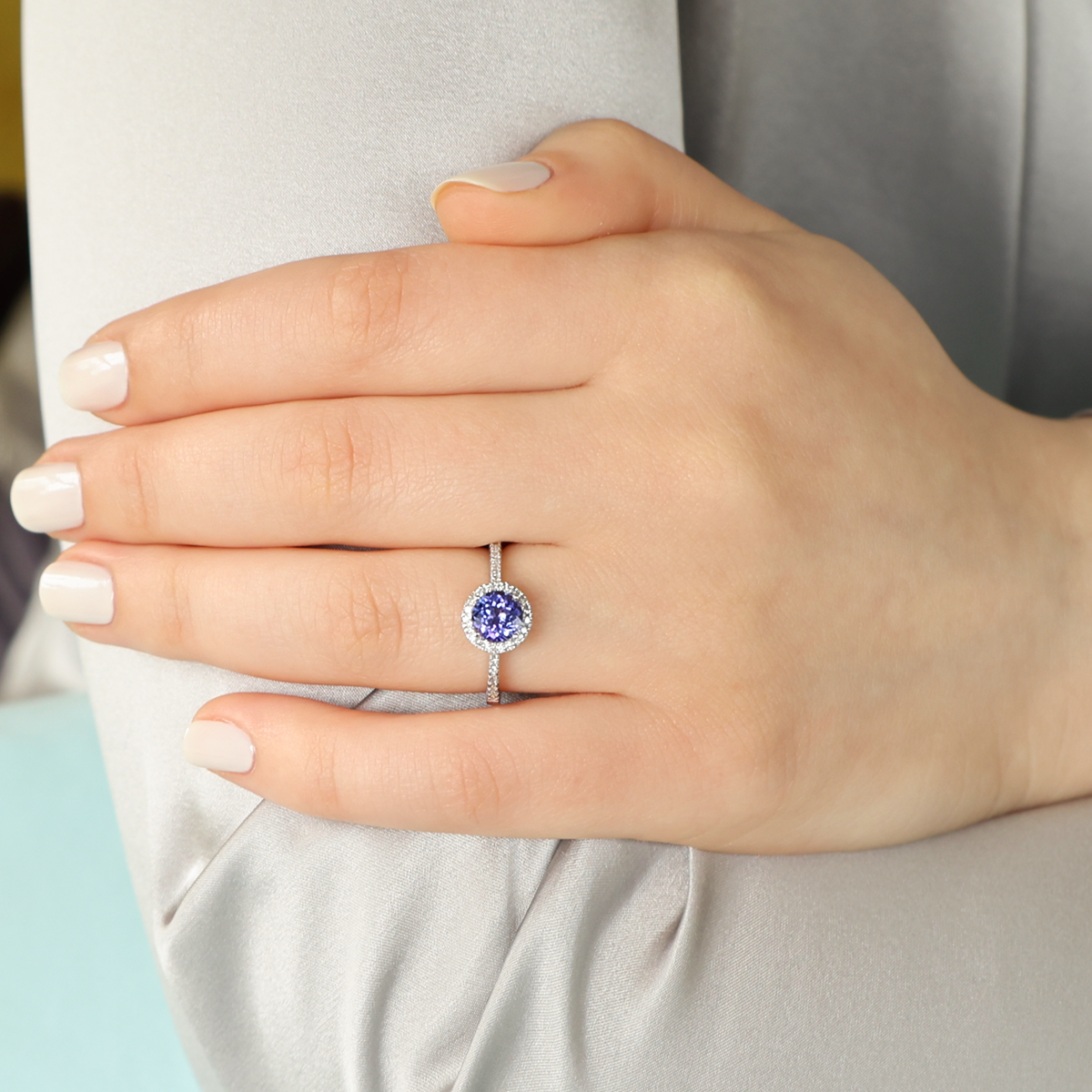 Model wears 18ct White Gold Tanzanite & Diamond Round Halo With Shoulders Ring