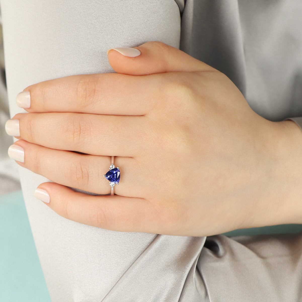 Model wears 18ct White Gold Trilliant Cut Tanzanite & Diamond Trilogy Ring