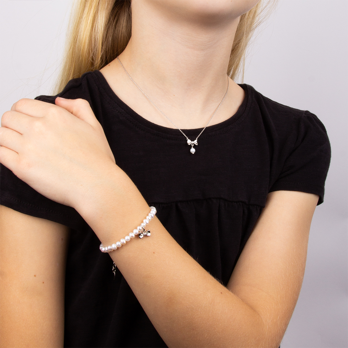 Model wears Sterling Silver Freshwater Pearl & Diamond Bow Charm Bracelet & Necklace
