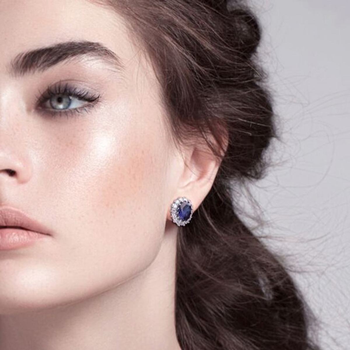 Models wears Sterling Silver Oval Shaped Blue Cubic Zirconia Cluster Stud Earrings