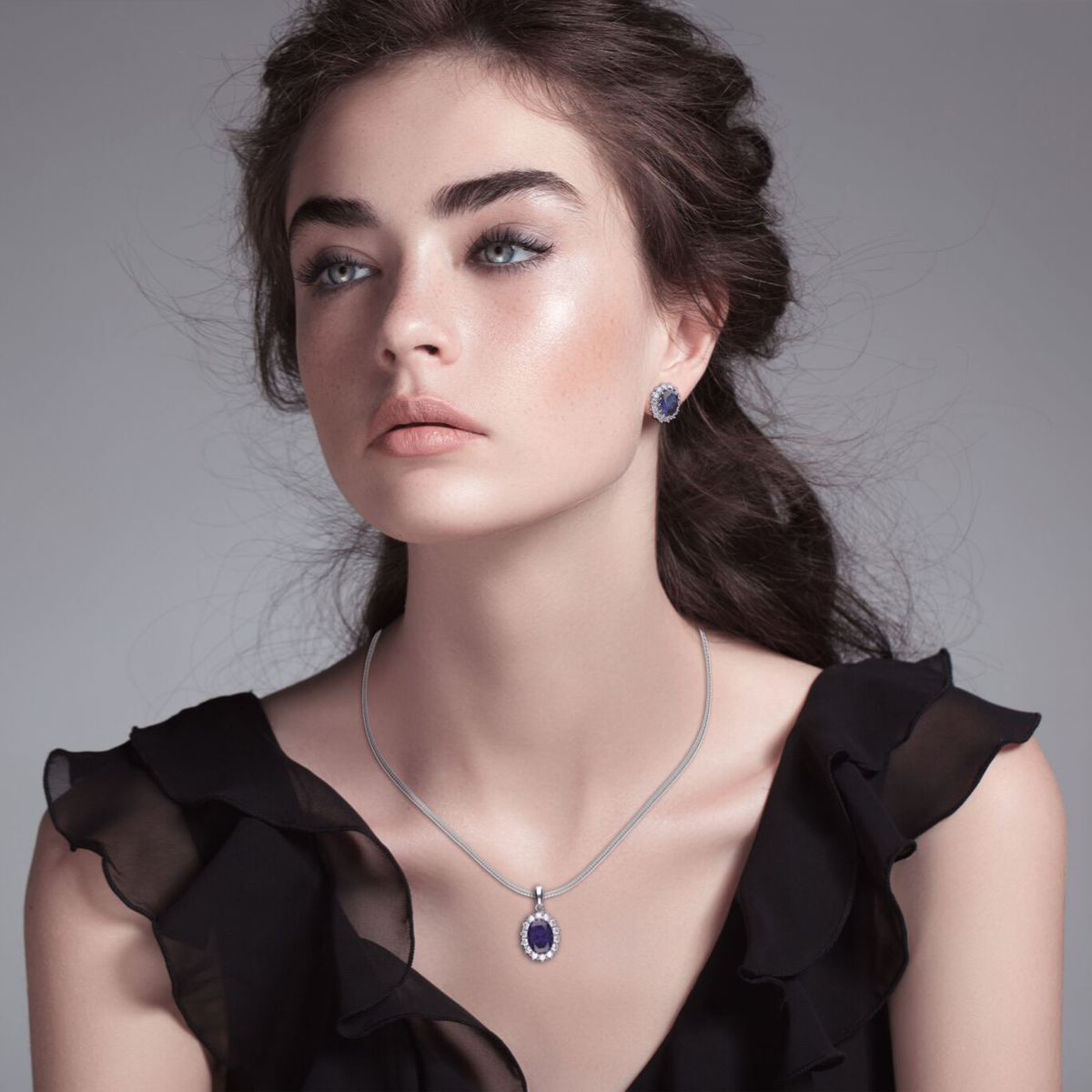 Model wears Sterling Silver Oval Shaped Blue Cubic Zirconia Cluster Pendant & Earrings